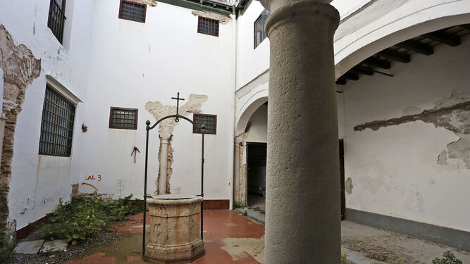 El aljibe que se encuentra en medio del patio, donde puede verse una de las catas que descubrió el resto de columnas del claustro menor.